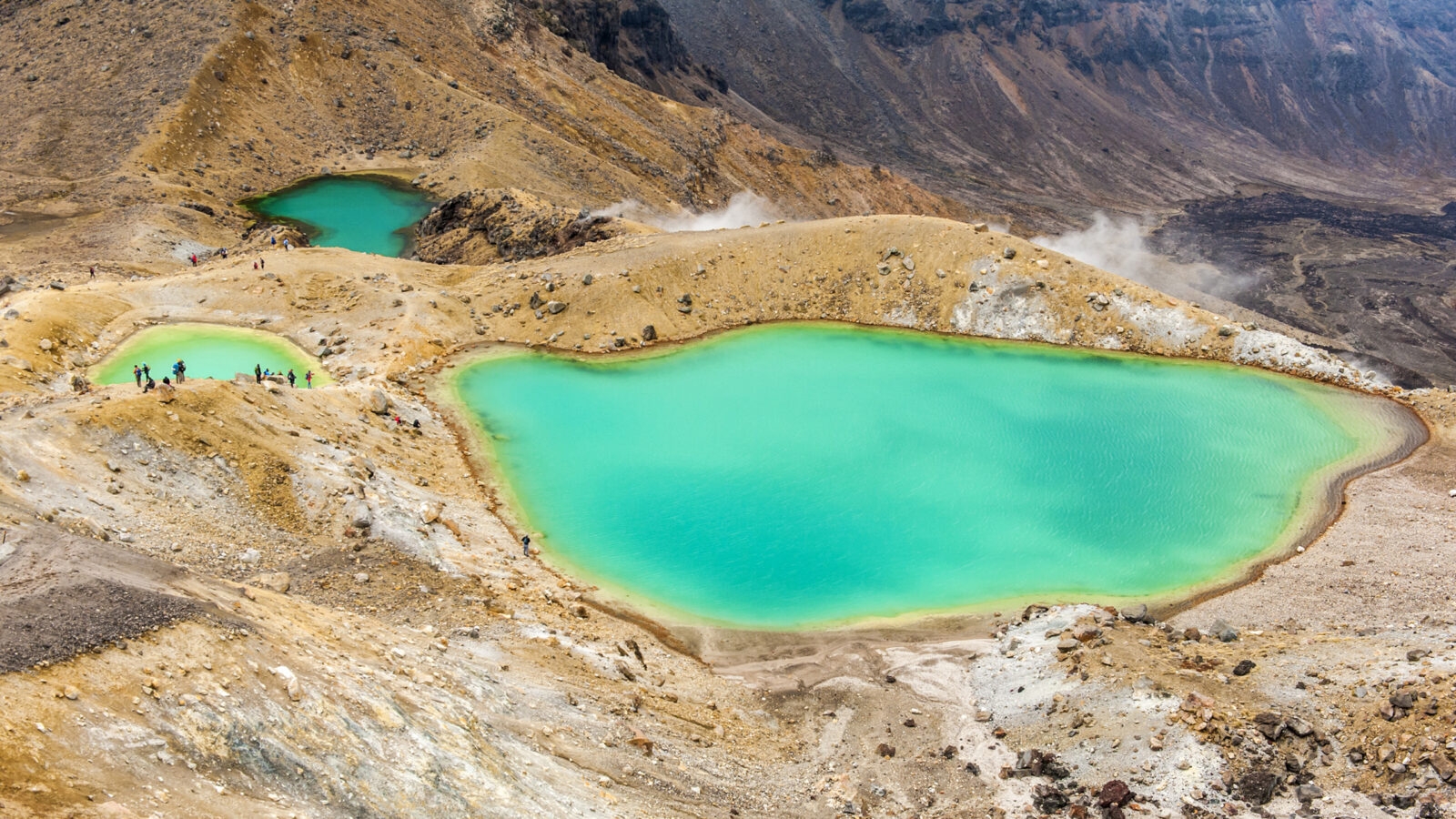 Three vibrant turquoise volcanic lakes surrounded by rocky, barren terrain.