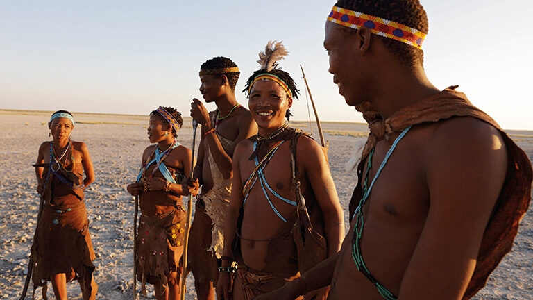 Luxury Botswana Tours - People dressed in traditional African tribal clothing standing in a dry plain