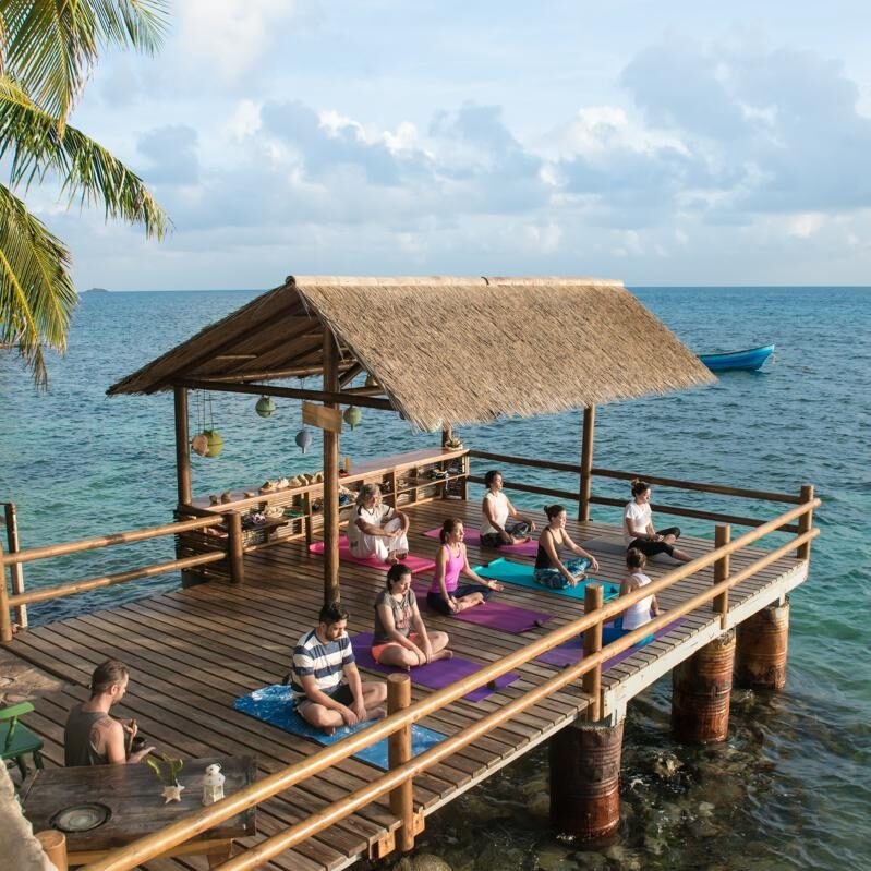 Jacada Colombia - people sitting on a covered wooden jetty by a calm blue ocean
