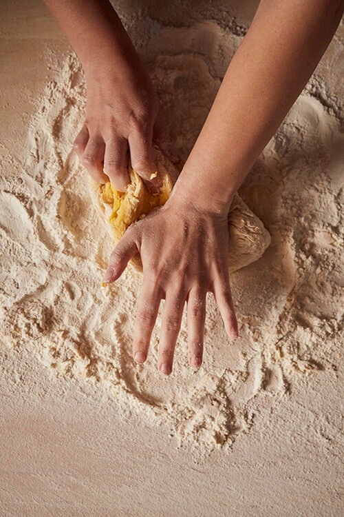Luxury Italy Tours - A shot of two hands making fresh dough, kneading the dough on a flour-covered surface