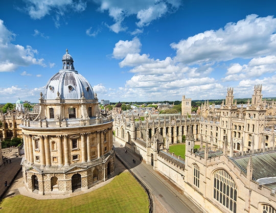 Aerial view of the Radcliffe Camera, a circular library with a dome, and surrounding historic Oxford University buildings for luxury England tours.