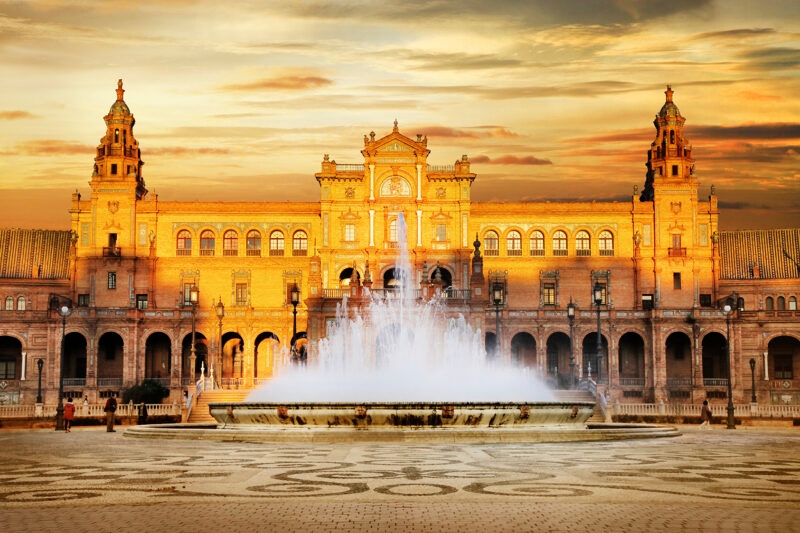 Plaza de España building in Seville glowing at sunset with a fountain in the center, ideal for luxury Spain vacations.
