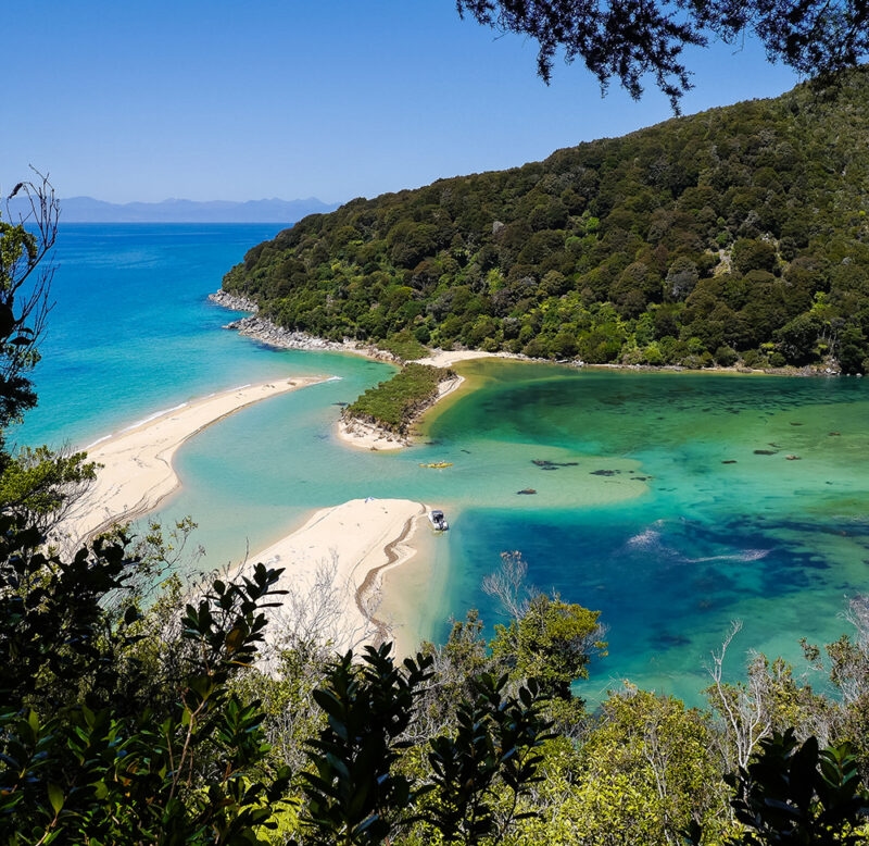 Aerial view of a turquoise lagoon and golden sand beaches during luxury New Zealand tours.