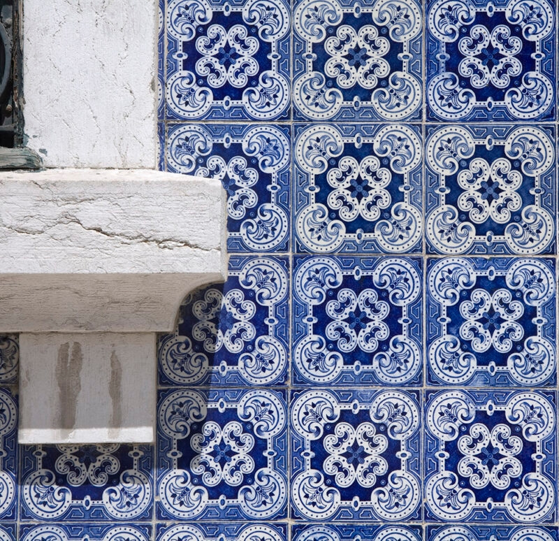 Close-up of traditional blue and white Portuguese Azulejo patterned tiles next to a white stone structure, perfect for luxury Portugal tours.