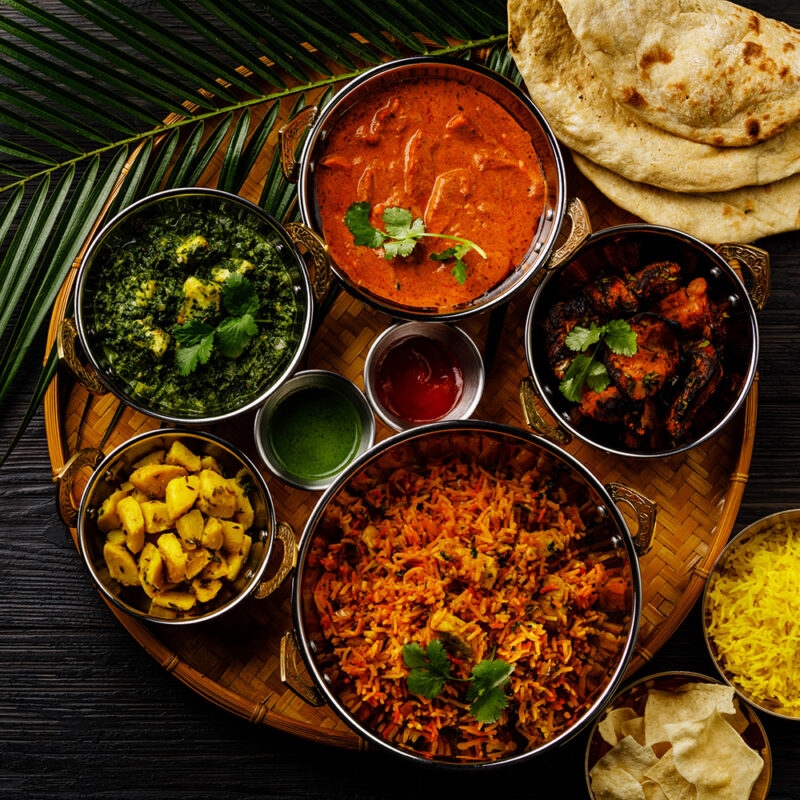 A traditional Indian thali platter with a variety of curries, rice, sides, and chapati, showcasing the cuisine on luxury India tours.
