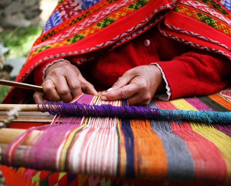 Close-up of a woman weaving brightly coloured yarns in Peru