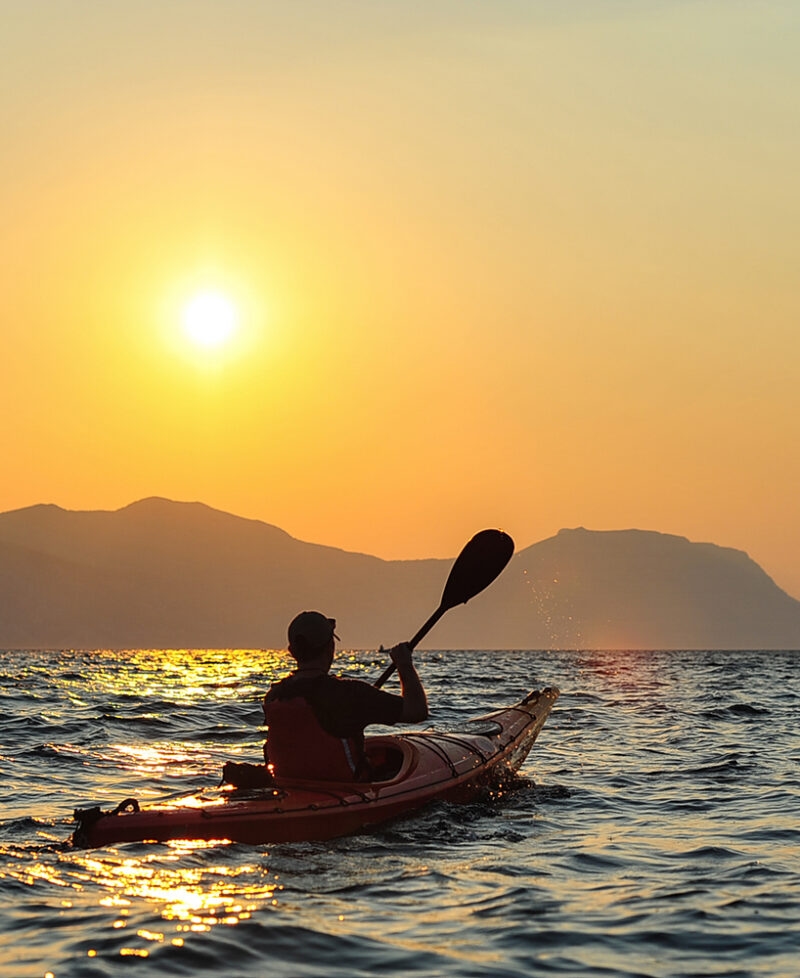 Silhouette of a person kayaking at sunset on the open sea, a feature of luxury Croatia vacations.