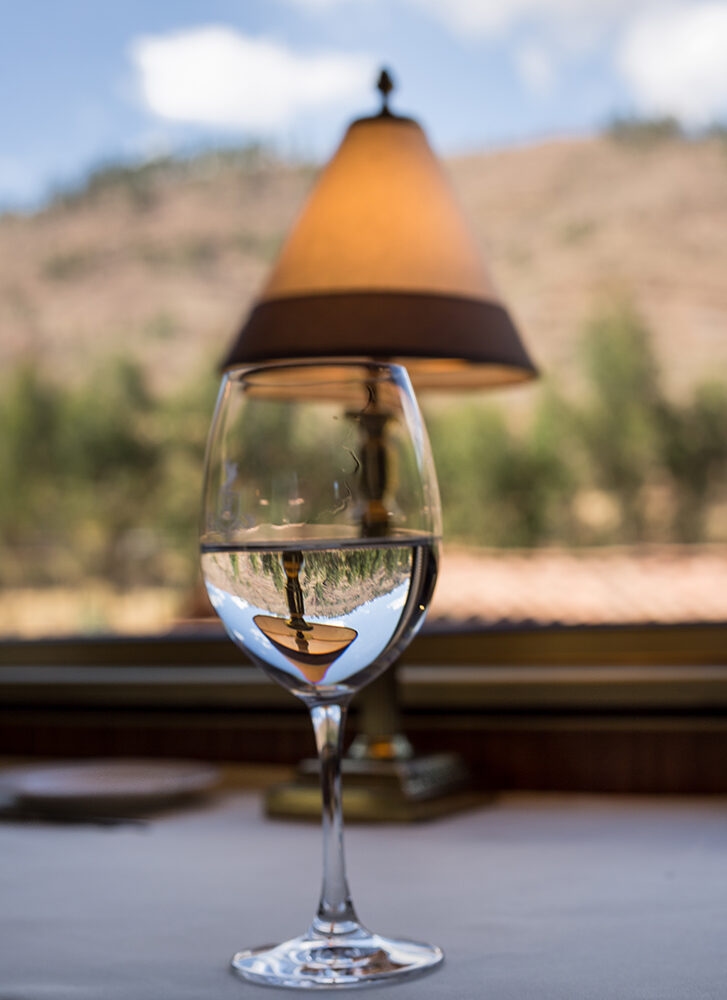 A water glass reflecting a lamp on luxury Peru train journeys.