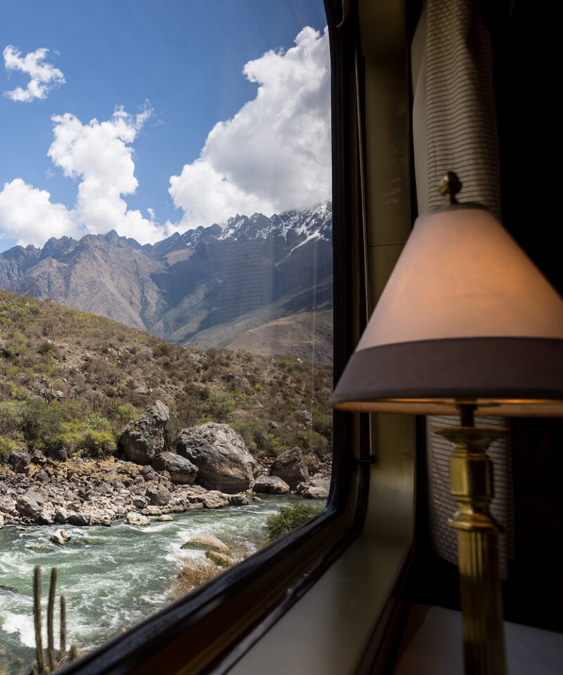 Interior of luxury Peru train tours with a view of a river and mountains through a window.