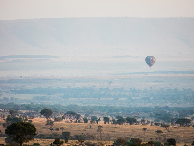 A hot air balloon drifting over the African savanna on luxury Serengeti National Park trips.