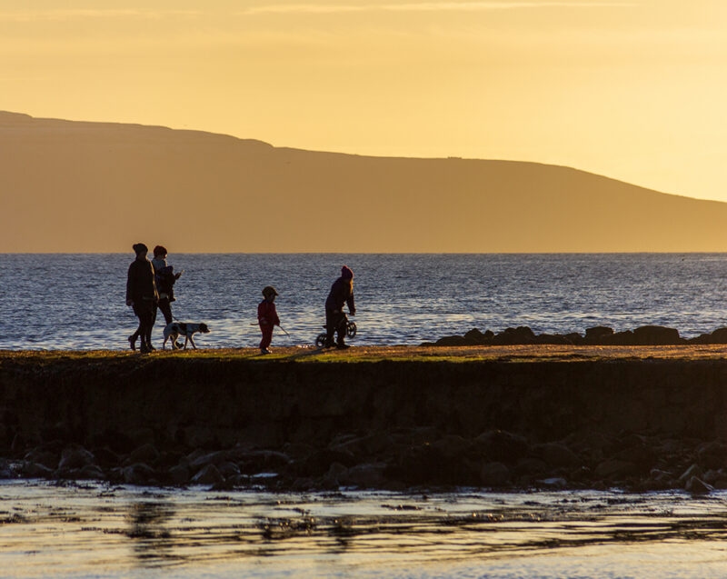 Family in silhouette walking on a jetty