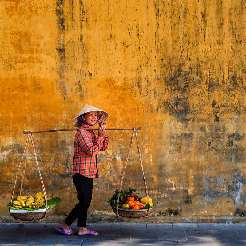 Luxury Vietnam Tours - Vietnamese woman selling tropical fruits, old town in Hoi An city, Vietnam