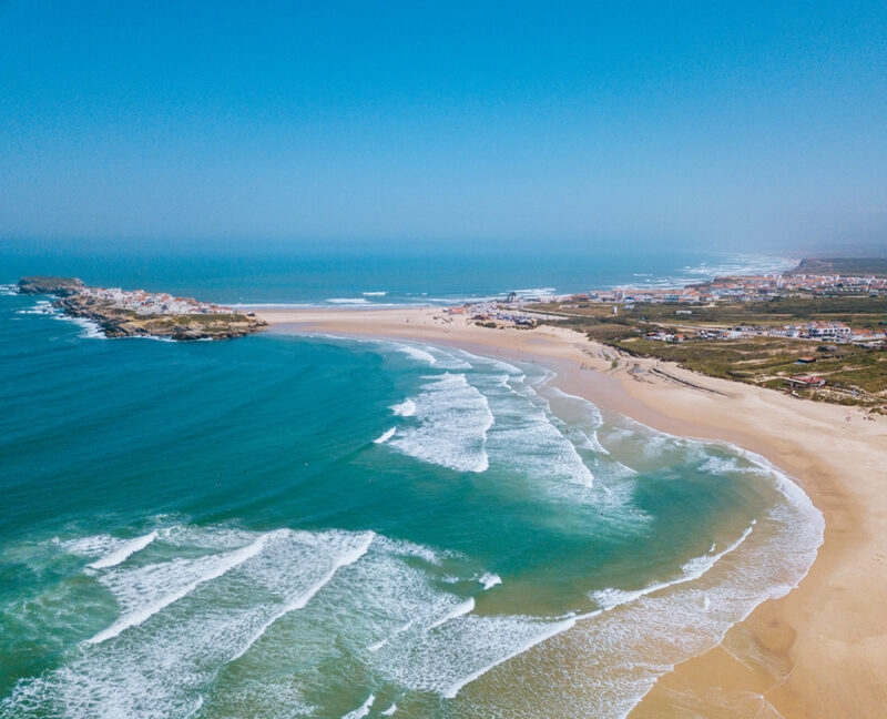 Aerial view of a long sandy beach and breaking waves on luxury Portugal trips.
