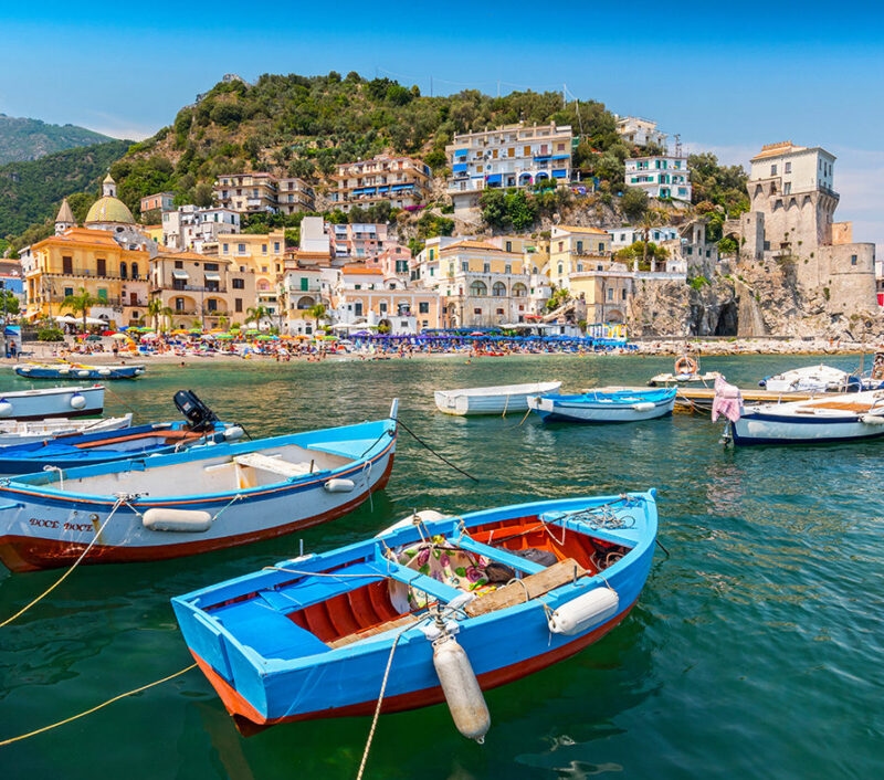 Blue and red wooden boats in a harbor during luxury Amalfi Coast holidays.