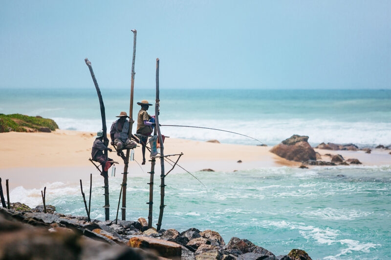 Local men fishing from tall wooden stilts in the ocean as part of luxury Indian Subcontinent trips.