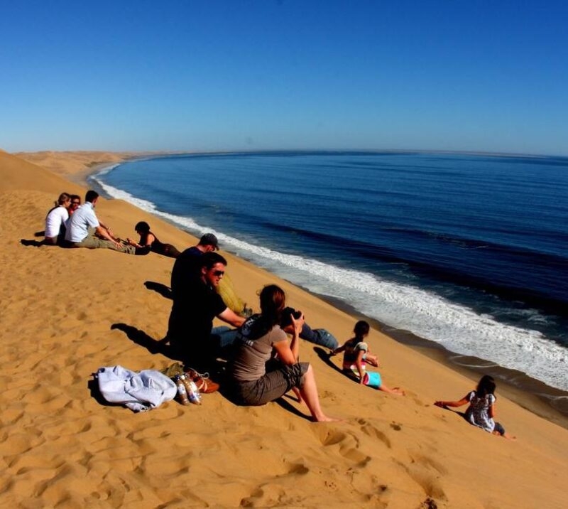 A family sitting on a golden sand beach by gentle water