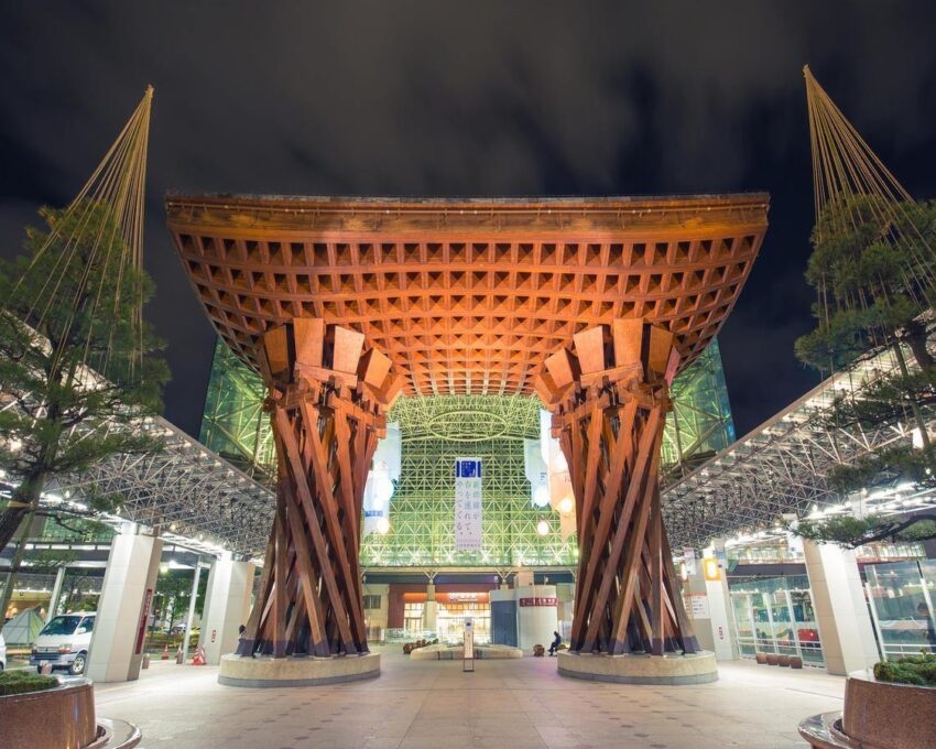 The illuminated wooden Tsuzumi Gate at Kanazawa Station at night.