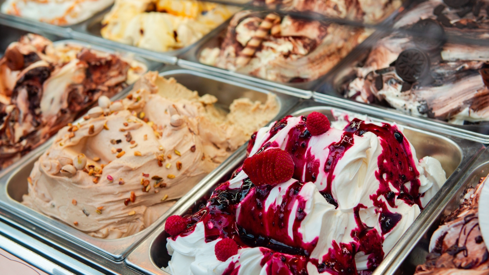 A close-up view of various flavors of Italian gelato in a display freezer.
