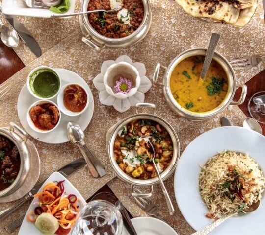 Aerial view of delicious Indian dishes, including curries, pickles, vegetables, rice, and breads