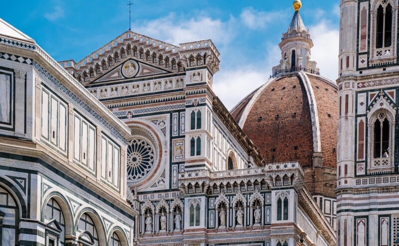 Detailed view of the marble facade and large red brick dome of the Florence Cathedral in Italy.