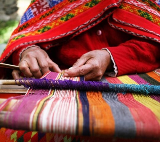 Close-up of a woman weaving brightly coloured yarns in Peru
