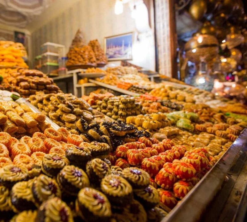 Close-up of various honey-soaked and chocolate-covered pastries arranged in a market display.