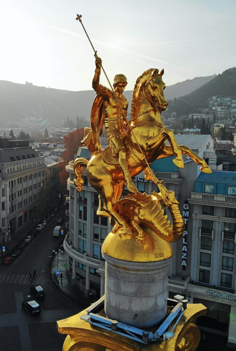 Golden statue of a knight on a horse in a city square on luxury Central Asia tours.
