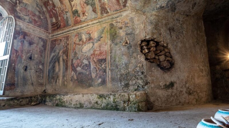 Detailed religious frescoes on the stone walls of an ancient cave during luxury Puglia trips.