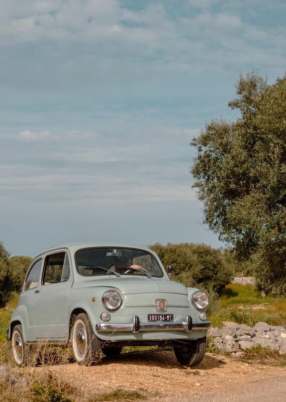 A vintage light blue car parked on a dirt road in the countryside on luxury Puglia tours.