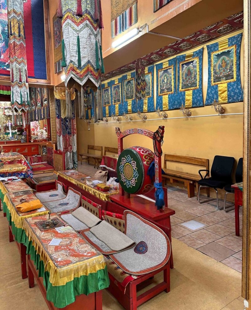Colorful interior of a Buddhist temple with silk hangings and a ceremonial drum, visited on luxury Mongolia trips.
