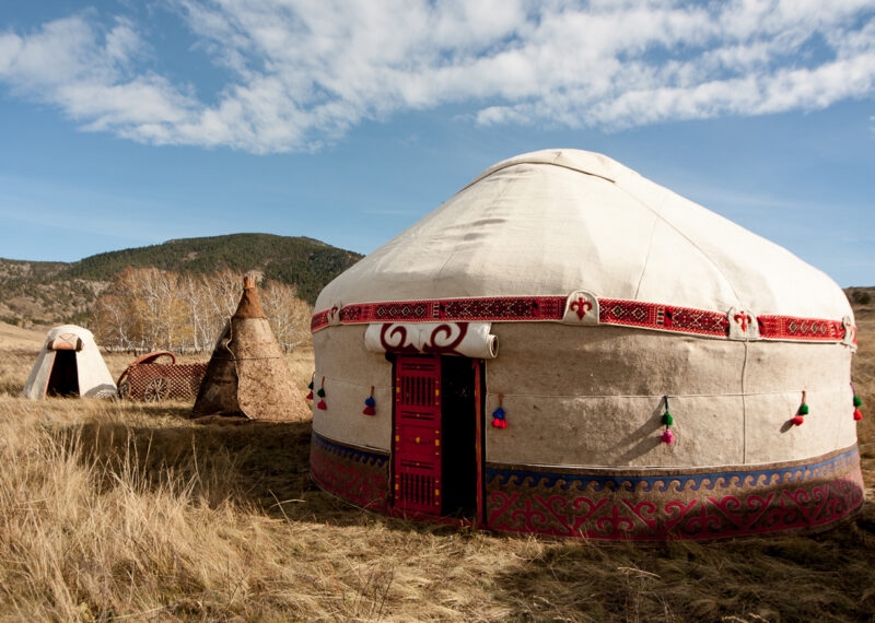 A traditional nomad yurt in a wide mountain meadow during luxury Central Asia holidays.