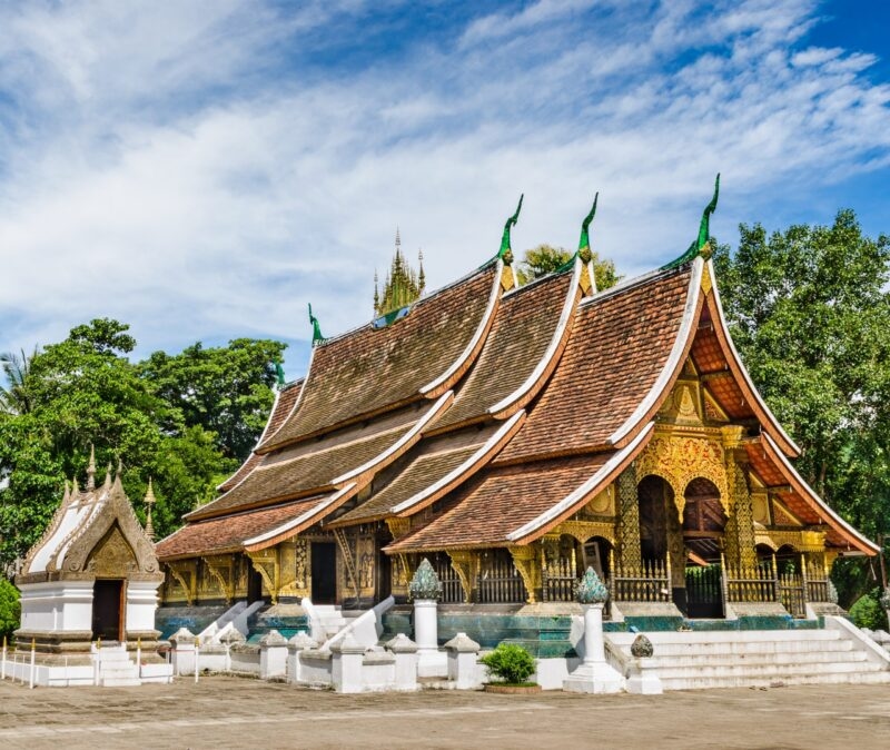 A traditional Laotian temple with a brown tiered roof and golden detail on luxury Asia grand tour holidays.