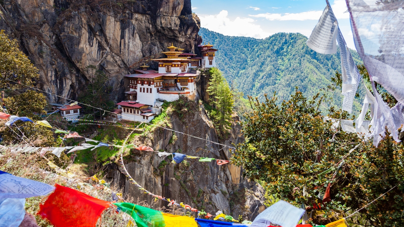 Tiger's Nest Monastery on cliffside with colorful prayer flags in Bhutan.