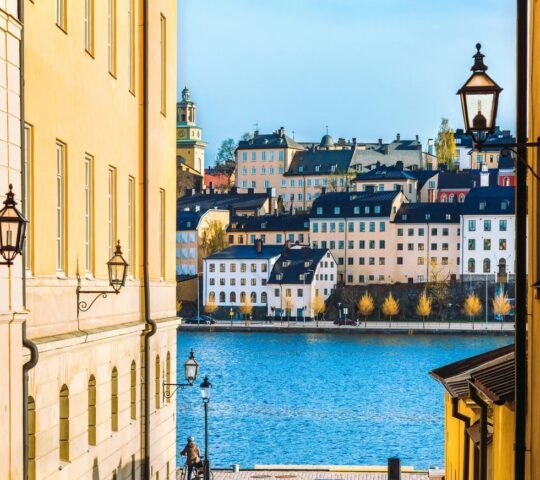 Touristic old street in Riddarholmen is a part of Gamla stan is old town of Stockholm city, Sweden. Exterior of houses, historic buildings and quay Baltic sea.