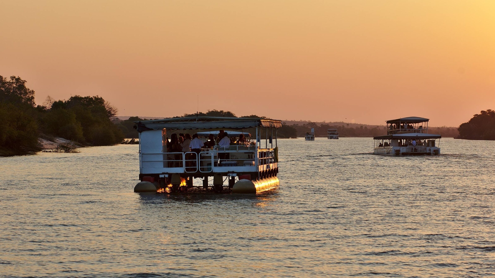 A safari ship cruising the Zambezi river at sunset