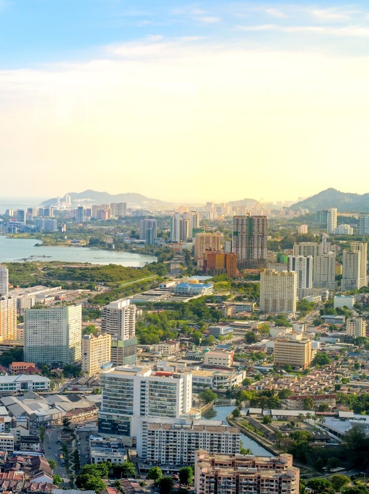 Aerial view of a coastal cityscape at sunset with buildings and a river.
