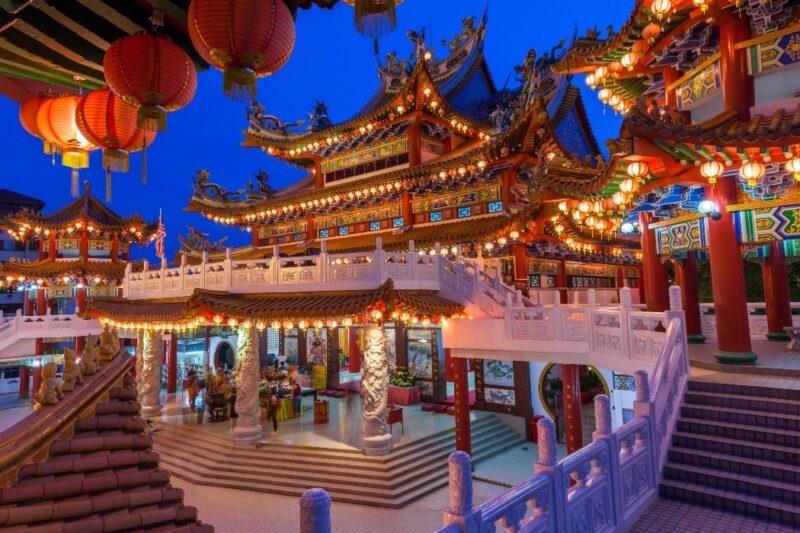 Illuminated traditional Chinese temple with intricate designs and red lanterns at dusk.