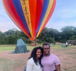 Two people in front of a colorful hot air balloon preparing for a flight.