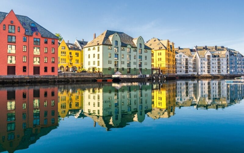 Colorful buildings reflecting in water under a clear blue sky.