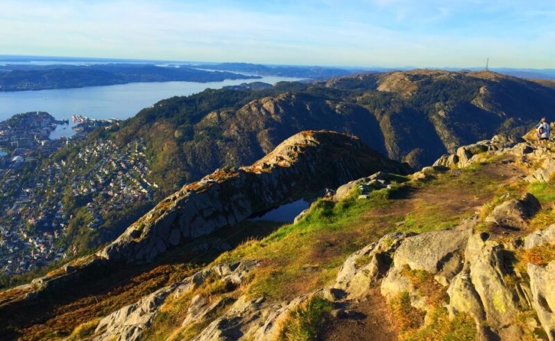 Mountainous landscape overlooking a town with waterways and distant hills under clear skies.