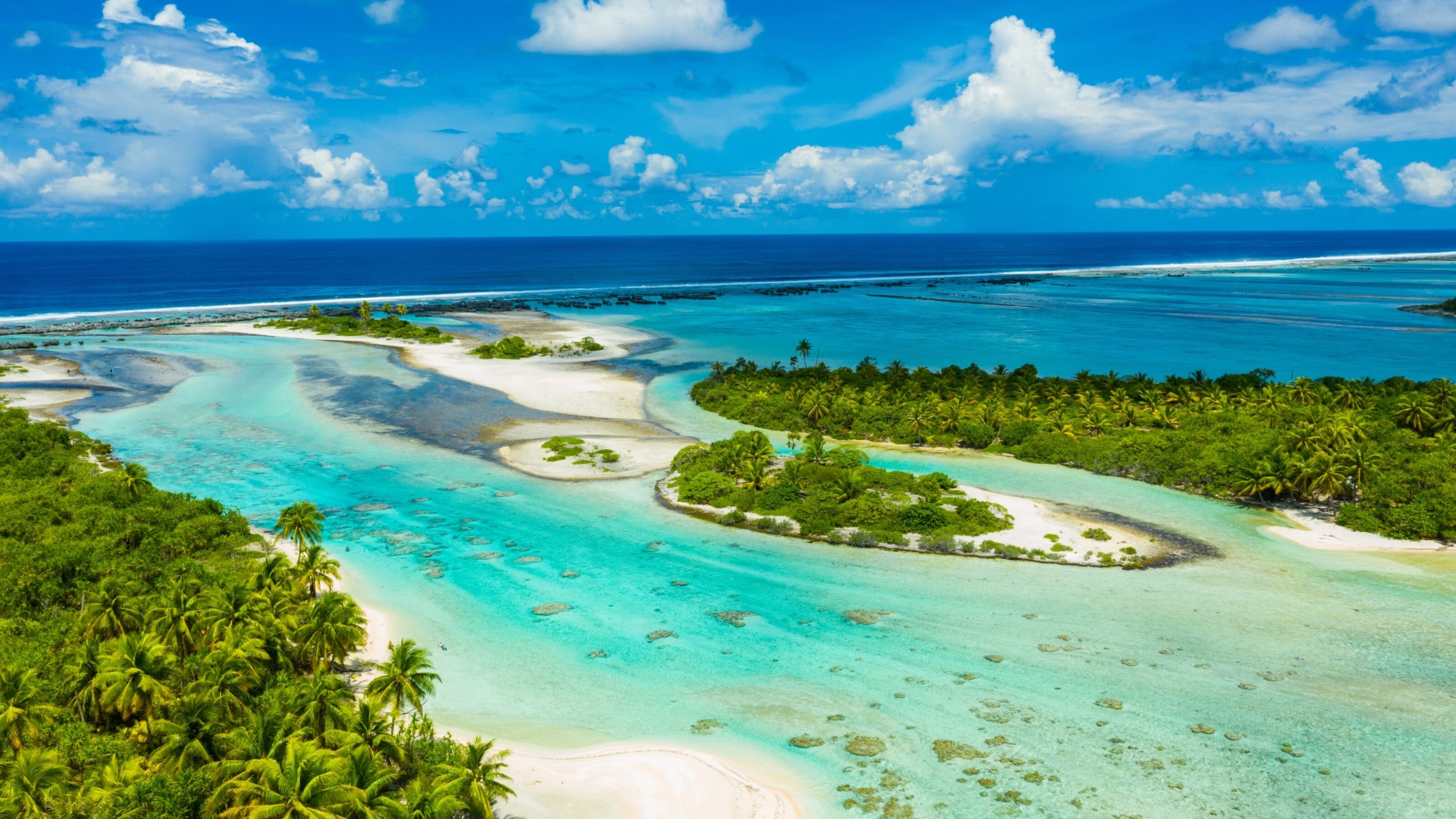 Aerial view of a tropical island with turquoise waters, lush greenery, and white sandy beaches.