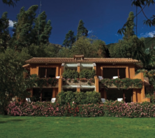 The exterior of Hotel Rio Sagrado surrounded by trees and flowers