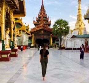 A person walking towards a temple with golden architecture, under a clear sky.