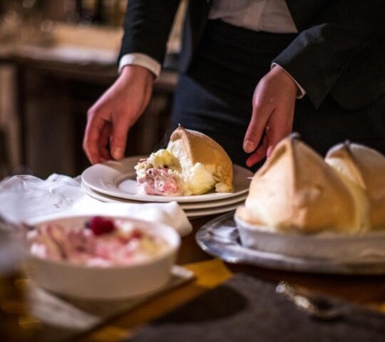 Waiter serving food in a dimly lit restaurant.