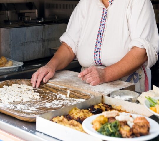 Person preparing food on a floured surface with dishes nearby.