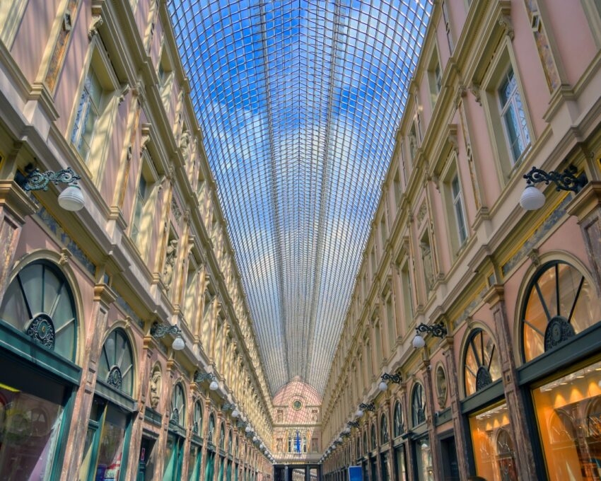 Elegant covered shopping arcade with arched glass roof and ornate facades.