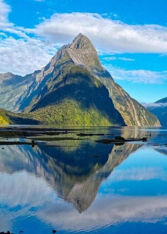 Mountain peak reflecting on a calm lake with clear blue skies.