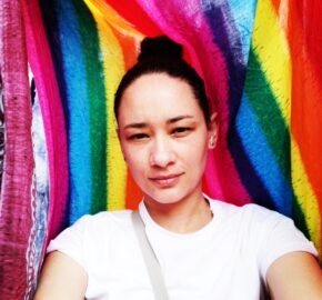 Person in white shirt against a colorful rainbow background.
