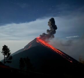 A volcano erupting at night with glowing lava and a starry sky in the background.