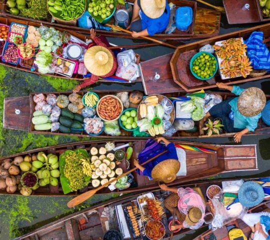 Aerial view of a vibrant floating market with vendors in boats selling fresh produce.